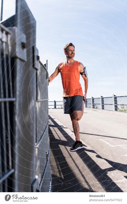 Mann joggt in der Stadt, macht eine Pause, dehnt sich trainieren sportlich Jogger fit Sportler dehnen strecken Joggen Jogging Fitness Gesundheit gesund Urban
