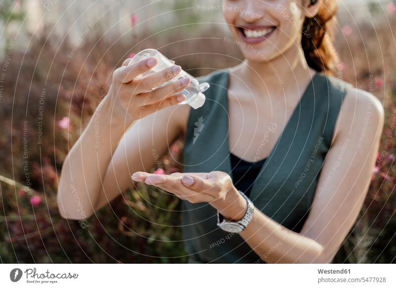 Nahaufnahme einer lächelnden Geschäftsfrau, die sich im Freien stehend die Hände mit Desinfektionsmittel wäscht Farbaufnahme Farbe Farbfoto Farbphoto Spanien
