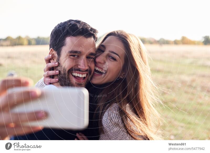 Ein glückliches Paar macht ein Selfie in einem Park Glück glücklich sein glücklichsein Parkanlagen Parks Selfies Pärchen Paare Partnerschaft Mensch Menschen