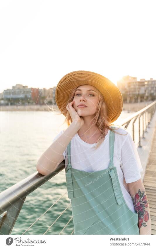Junge Frau, die einen Tag am Meer verbringt und auf einer Brücke steht stehend Muße Individuell Stil stylisch Lifestyles Beach Beaches Straende Strände