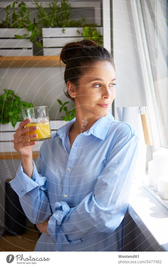 Junge Frau trinkt Orangensaft in ihrer Küche Glas Trinkgläser Gläser Trinkglas Frische frisch optimistisch Optimismus tagträumen Tagtraum Gesunde Ernährung