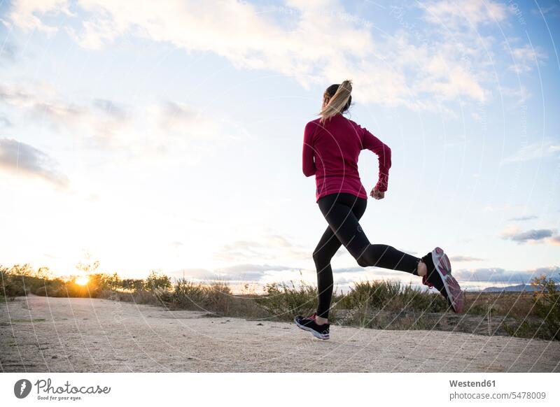 Junge Frau joggt allein auf dem Lande rennen früh Frühe Morgen blaue blauer blaues rote roter rotes Muße Anreiz Ansporn Antrieb motivieren motiviert trainieren