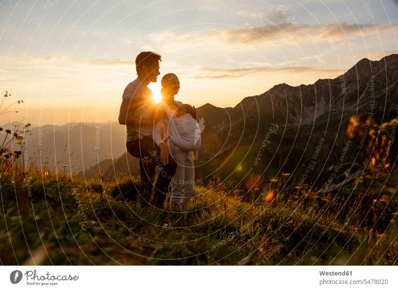 Deutschland, Bayern, Oberstdorf, Familie mit kleiner Tochter bei einer Wanderung in den Bergen bei Sonnenuntergang Familien wandern Töchter halten Mensch