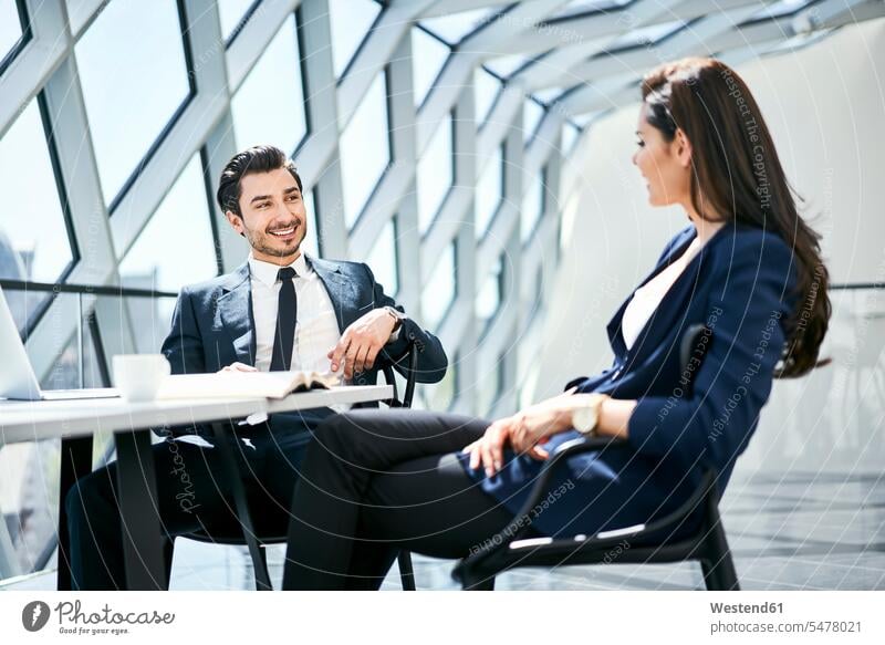 Geschäftsfrau und Geschäftsmann im Gespräch am Schreibtisch im modernen Büro Geschäftsfrauen Businesswomen Businessfrauen Businesswoman sprechen reden