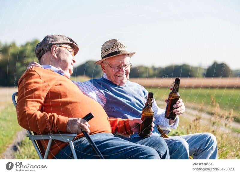 Zwei alte Freunde sitzen auf den Feldern, trinken Bier und reden über alte Zeiten sprechen sitzend sitzt Beste Freunde Bester Freund Alkohol