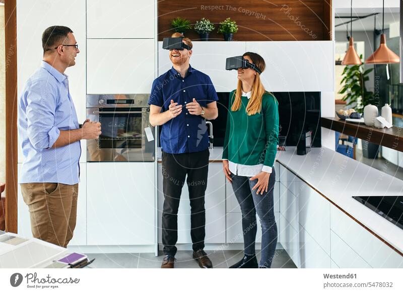 Paar mit VR-Brille beim Einkaufen für eine neue Küche im Showroom Leute Menschen People Person Personen Kunden Kundschaft Job Berufe Berufstätigkeit