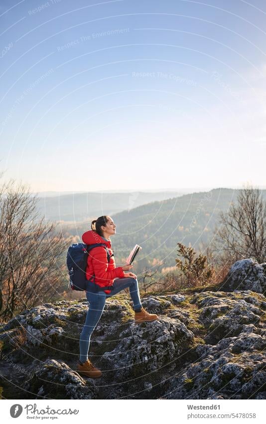 Frau auf einer Wanderung in den Bergen hält Karte und genießt schöne Aussicht genießen geniessen Genuss Ausflug Ausflüge Kurzurlaub Ausfluege Wandertour