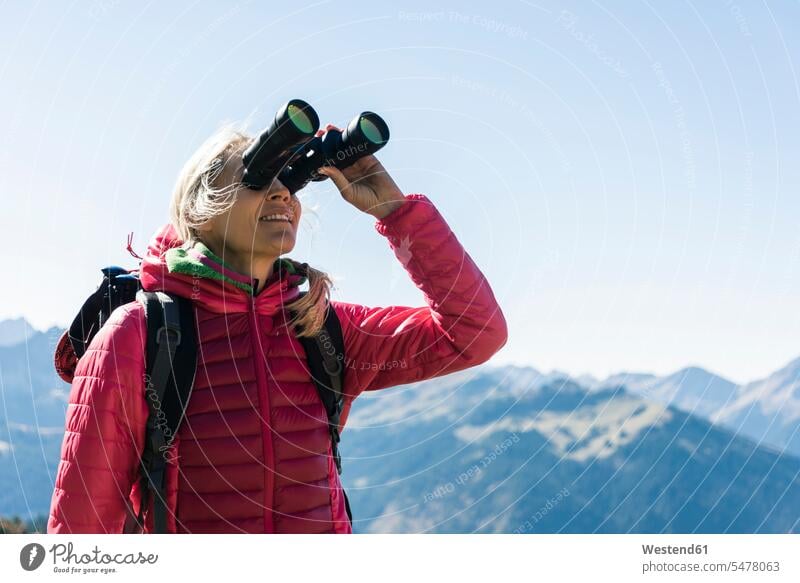 Österreich, Tirol, Frau schaut beim Wandern durch ein Fernglas schauen sehend Wandertour weiblich Frauen wandern Wanderung Ferngläser Feldstecher Fernglaeser