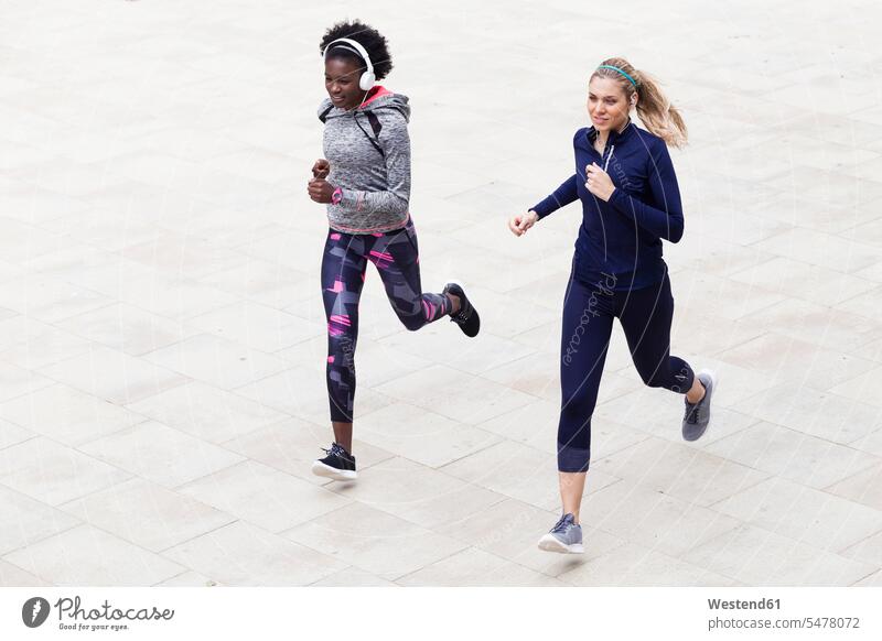 Zwei sportliche junge Frauen laufen zusammen in der Stadt staedtisch städtisch Gemeinsam Zusammen Miteinander weiblich Joggen Jogging Freundinnen rennen