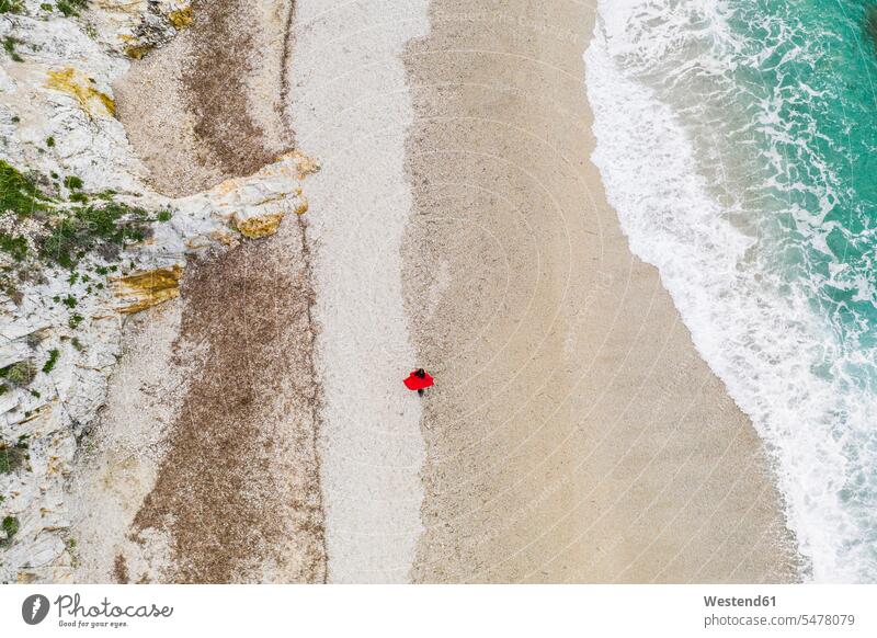 Italien, Elba, Frau mit rotem Mantel beim Strandspaziergang, Luftaufnahme mit Drohne Fernweh Reiselust Allein alleine einzeln erkunden Erforschung Erkundung