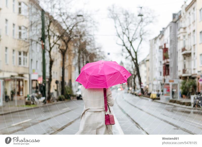 Rückansicht einer Frau mit rosa Regenschirm auf der Straße geschäftlich Geschäftsleben Geschäftswelt Geschäftsperson Geschäftspersonen Businessfrau