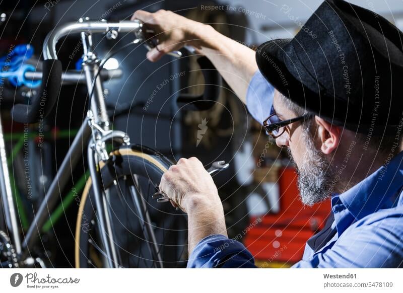 Mann arbeitet am Fahrrad in der Werkstatt Bikes Fahrräder Räder Rad Werkstätte Werkstaette Werkstaetten Werkstätten arbeiten Arbeit Männer männlich Raeder