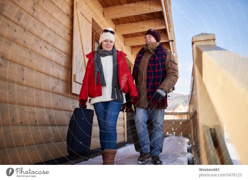 Ausgewachsenes Paar mit Koffern geht im Winter auf Berghütte Pärchen Paare Partnerschaft gehen gehend Berghütten Berghuette Hütte Mensch Menschen Leute People