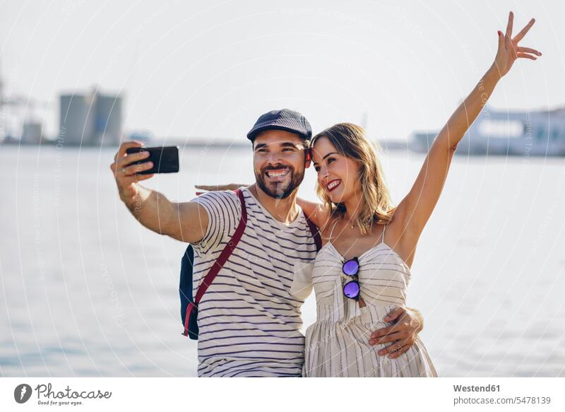 Spanien, Andalusien, Malaga, glückliches Touristenpaar macht Selfie mit Smartphone an der Küste Kueste Kuesten Küsten Selfies Glück glücklich sein glücklichsein