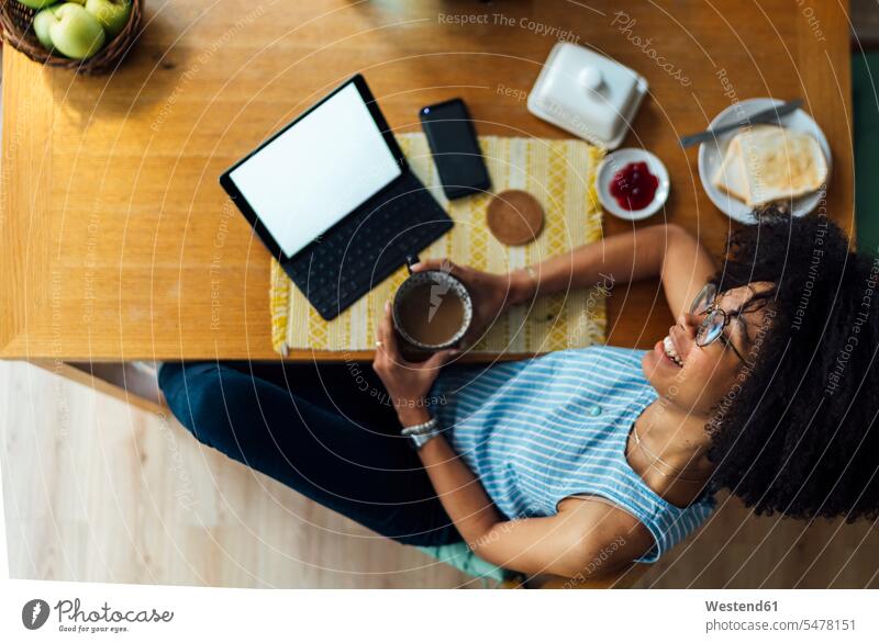 Geschäftsfrau mit digitalem Tablet und Frühstück am Schreibtisch, die zu Hause sitzt und nachdenkt Farbaufnahme Farbe Farbfoto Farbphoto Freizeitkleidung