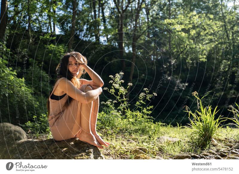 Porträt einer jungen Frau, die auf einem Felsen im Wald sitzt, Garrotxa, Spanien Leute Menschen People Person Personen Europäisch Kaukasier kaukasisch erwachsen