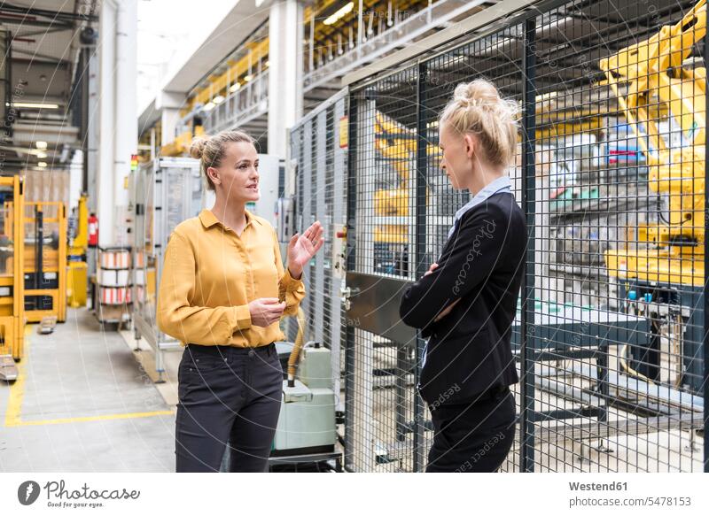 Zwei Frauen im Gespräch in der Fabrikhalle mit Industrieroboter sprechen reden Industriehallen Fabrikhallen weiblich Fabriken Roboter Halle Hallen Erwachsener