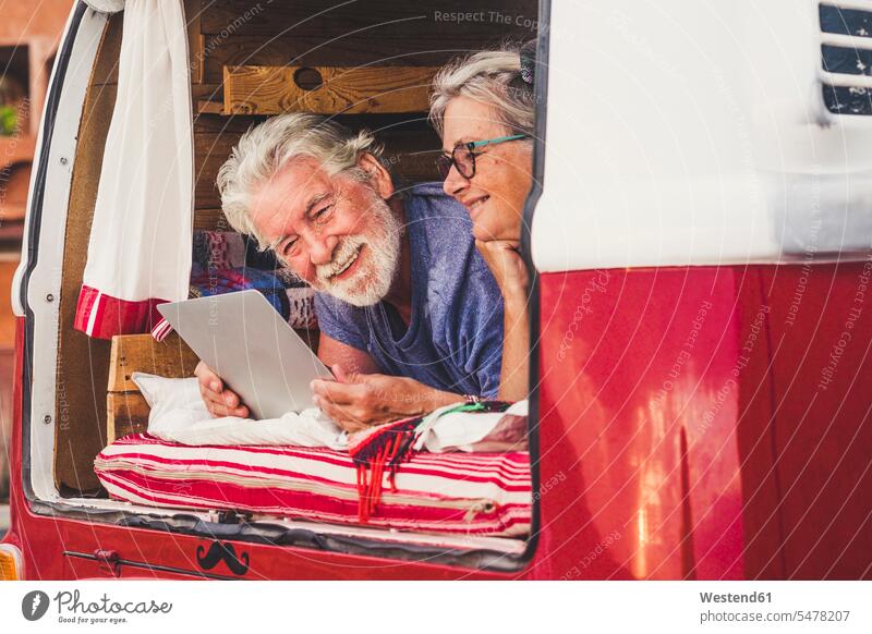 Älteres Paar, das in einem Oldtimer-Van reist, im Kofferraum liegend, mit digitalem Tablet Touristen Transport Transportwesen KFZ Verkehrsmittel Automobil Autos