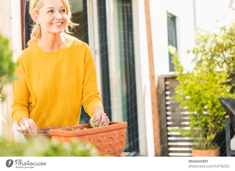 Porträt einer lächelnden reifen Frau bei der Gartenarbeit auf der Terrasse entspannen relaxen freuen geniessen Genuss Glück glücklich sein glücklichsein Farben