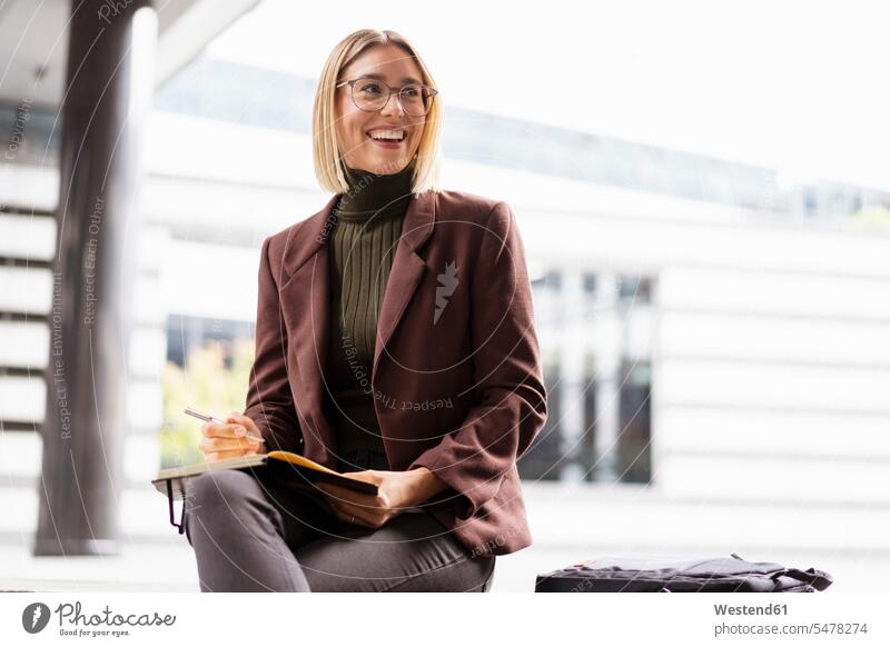 Lächelnde junge Geschäftsfrau mit Notizbuch in der Stadt Leute Menschen People Person Personen Europäisch Kaukasier kaukasisch 1 Ein ein Mensch eine