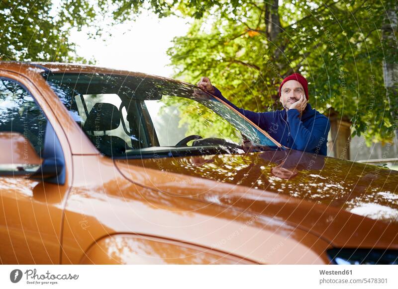 Reifer Mann lehnt an Auto in der Natur Wagen PKWs Automobil Autos aufstützen aufgestuetzt aufgestützt Männer männlich Kraftfahrzeug Verkehrsmittel KFZ