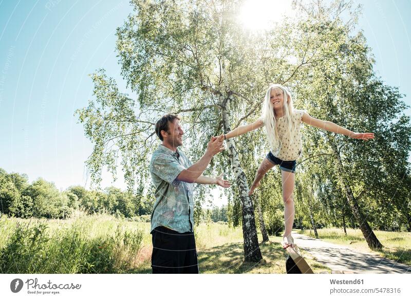 Vater hilft Tochter beim Balancieren auf einer Parkbank ausgeglichen Ausgeglichenheit Gleichgewicht Balance Jahreszeiten Frühjahr Lenz sommerlich Sommerzeit