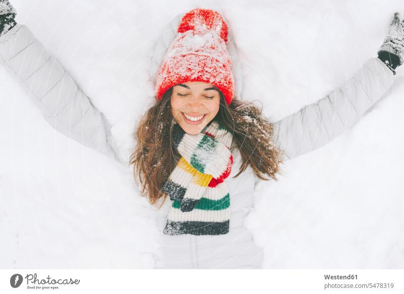 Porträt einer glücklichen Frau auf Schnee liegend Handschuhe Schals Jahreszeiten winterlich Winterzeit entspannen relaxen entspanntheit relaxt freuen Frohsinn