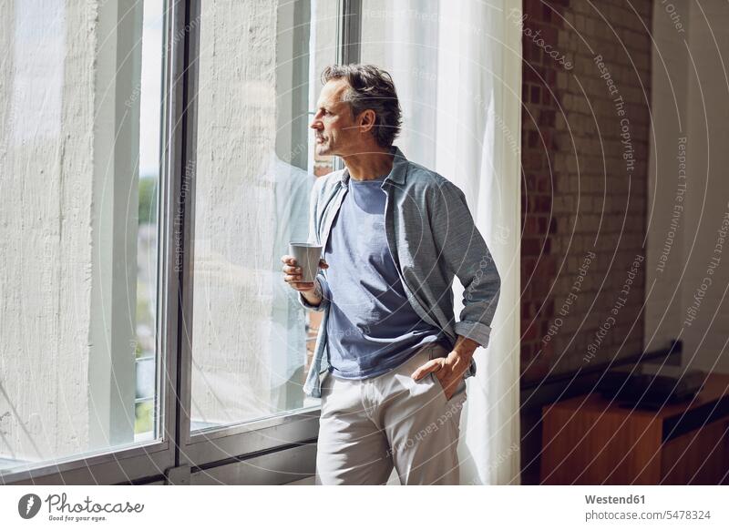 Älterer Mann schaut in einer Dachgeschosswohnung aus dem Fenster entspannen relaxen entspanntheit relaxt stehend steht Innenarchitektur Muße Individuell Stil