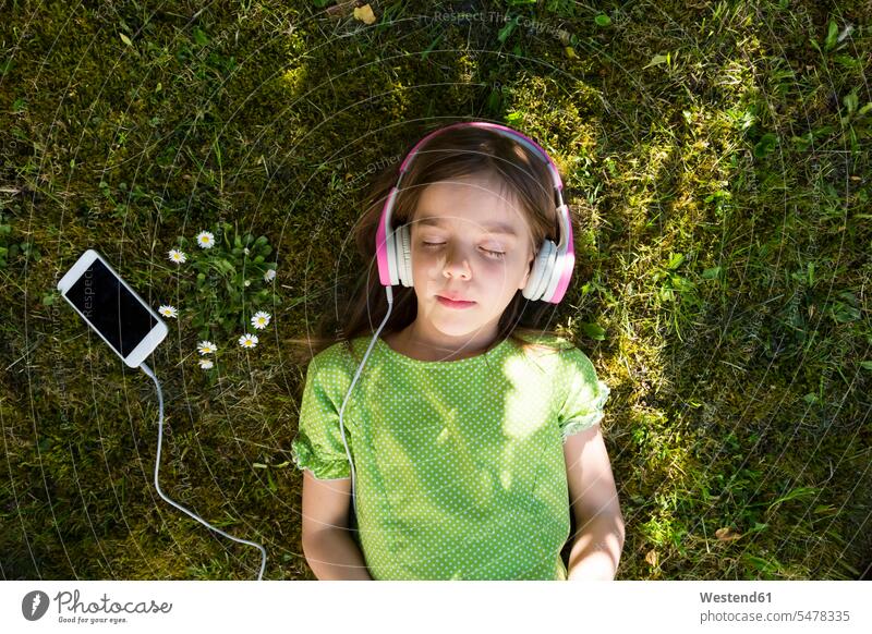 Mädchen liegt auf der Wiese und hört Musik mit Kopfhörern und Smartphone hören hoeren Portrait Porträts Portraits iPhone Smartphones liegen liegend Wiesen