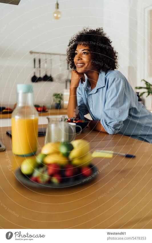 Frau mit einem gesunden Frühstück in ihrer Küche lächeln Küchen morgens Morgen früh Frühe stehen stehend steht frühstücken Obst Früchte Frau mittleren Alters