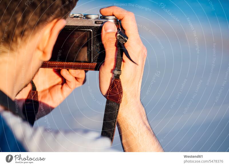 Nahaufnahme eines jungen Mannes beim Fotografieren mit einer altmodischen Kamera Männer männlich fotografieren Fotoapparat Fotokamera Erwachsener erwachsen