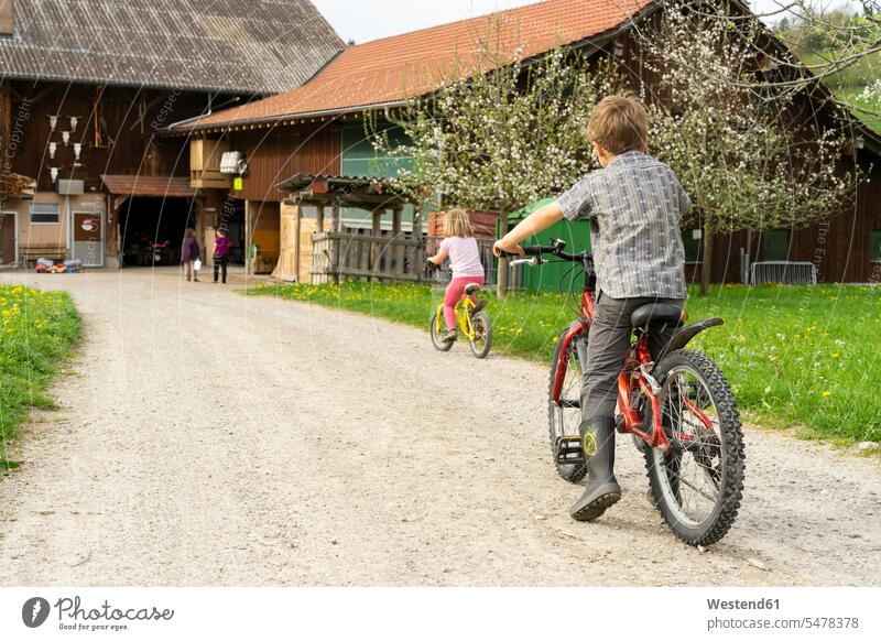 Mädchen und Junge fahren Fahrrad auf einem Bauernhof Raeder Räder Bike Bikes Fahrräder Rad bescheiden Bescheidenheit genügsam auf dem Land auf dem Lande Muße