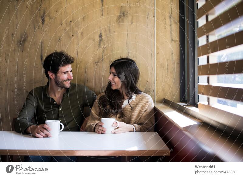 Glückliches Paar trinkt Kaffee in einem Cafe Tische sitzend sitzt freuen glücklich sein glücklichsein Muße Miteinander Zusammen Lifestyles Bindung Gemeinschaft