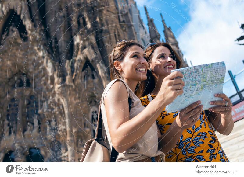 Lächelnde Freunde mit der Karte im Kampf gegen die Sagrada Familia in Barcelona, Katalonien, Spanien Farbaufnahme Farbe Farbfoto Farbphoto Außenaufnahme außen