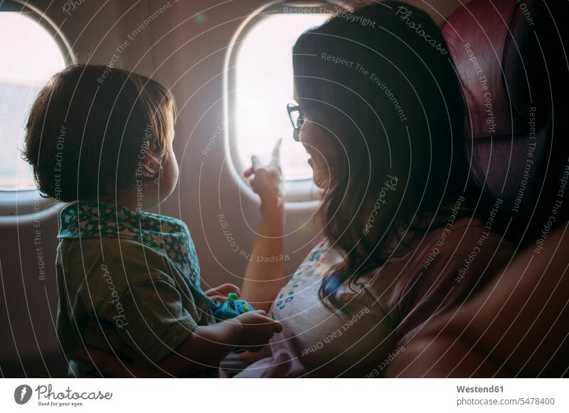 Mutter und kleine Tochter im Flugzeug schauen aus dem Fenster Mamas Mami Mutti Mütter Muetter Mamis Muttis reisen Travel verreisen Weg Reise Flugreise