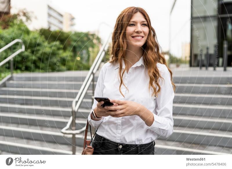 Junge Geschäftsfrau, die eine Treppe hinuntergeht und ein Smartphone benutzt benutzen benützen Treppenaufgang unterwegs auf Achse in Bewegung Urban städtisch