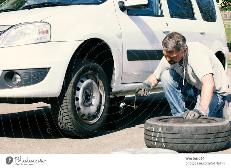 Erwachsener Mann wechselt Autoreifen, Draufsicht wechseln ändern Reifen Reifenwechsel Radwechsel Männer männlich erwachsen Mensch Menschen Leute People Personen