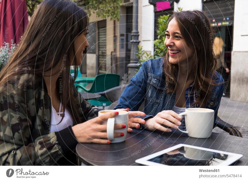 Glückliche junge Frauen mit Kaffee sitzen in außerhalb Cafe zusammen in Madrid, Spanien Leute Menschen People Person Personen Europäisch Kaukasier kaukasisch 2