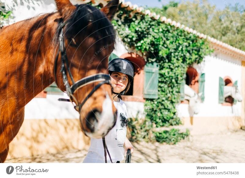 Teenager mit Down-Syndrom kümmert sich um Pferd und bereitet Pferd zum Reiten vor Helme Jahreszeiten sommerlich Sommerzeit freuen Glück glücklich sein