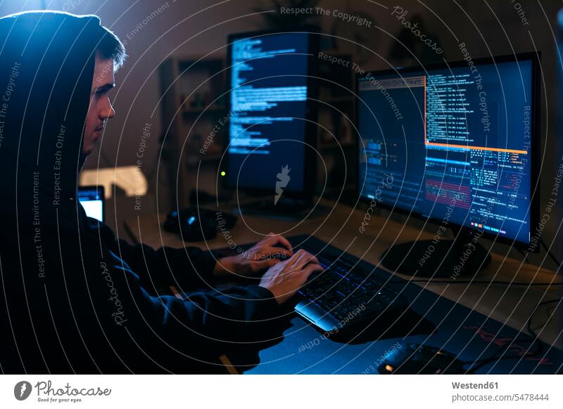 Junger Mann benutzt Computer bei der Arbeit am Tisch Farbaufnahme Farbe Farbfoto Farbphoto Innenaufnahme Innenaufnahmen innen drinnen Hacker Programmierer