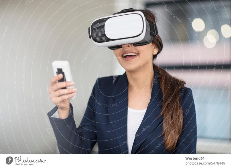 Lächelnde Geschäftsfrau mit VR-Brille im Büro Brillen Geschäftsfrauen Businesswomen Businessfrauen Businesswoman lächeln Frau weiblich Frauen Virtuelle Realität