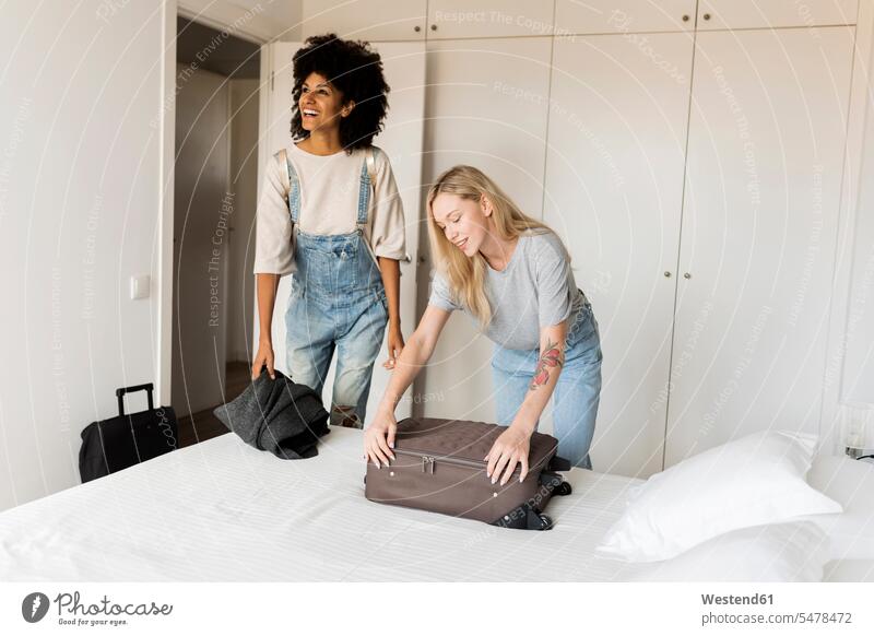 Zwei lächelnde Frauen mit Gepäck bei der Ankunft in der Unterkunft Freundin Reisegepäck ankommen eintreffen weiblich Unterkünfte Erwachsener erwachsen Mensch