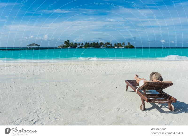 Malediven, Ari Atoll, Nalaguraidhoo, Sun Island Resort, Rückenansicht einer Frau beim Entspannen am Strand Sonnenliege Sonnenliegen Entspannung relaxen