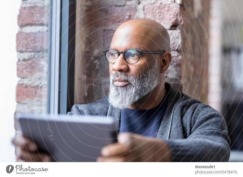 Porträt eines nachdenklichen Mannes mit Tablette, der aus dem Fenster schaut Portrait Porträts Portraits schauen sehend Männer männlich Tablet Computer