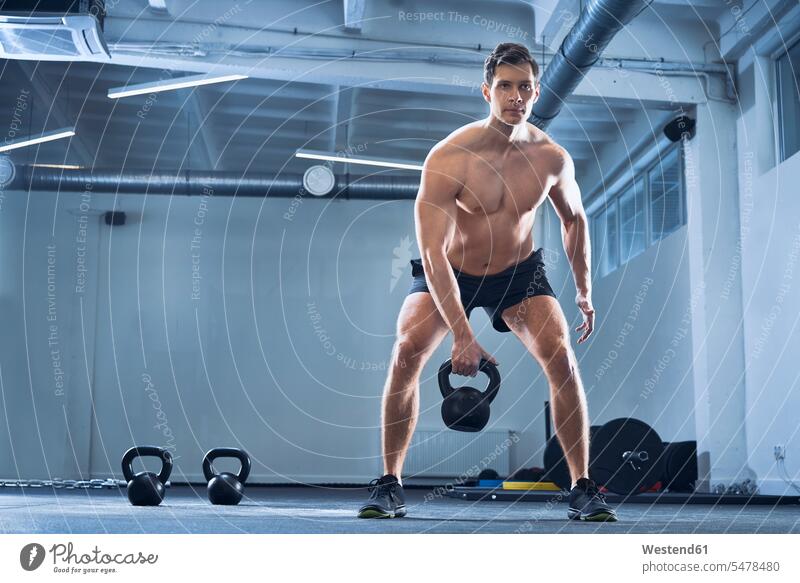 Athlet, der im Fitnessstudio Kettlebell-Schwungübungen macht Mann Männer männlich Workout Rundgewicht Kugelhantel Kettlebells Fitnessclubs Fitnessstudios