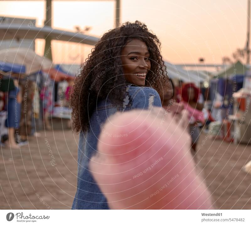 Porträt einer glücklichen jungen Frau mit rosa Zuckerwatte auf dem Strassenmarkt abends freuen Glück glücklich sein glücklichsein zufrieden Farben Farbtoene
