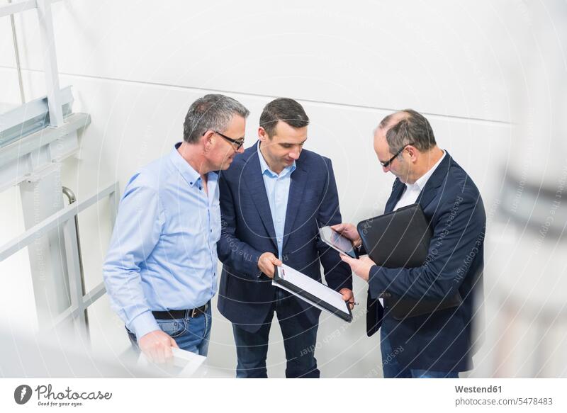 Drei Geschäftsleute bei einer Diskussion in einer Fabrik Leute Menschen People Person Personen Europäisch Kaukasier kaukasisch Gruppe von Menschen