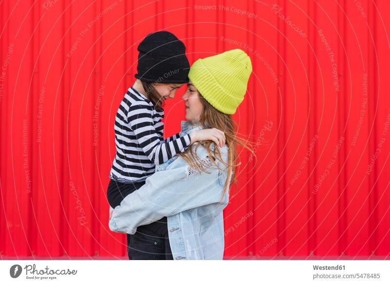 Teenager-Mädchen Kopf an Kopf mit ihrer jüngeren Schwester Mütze Mützen Beziehung Vertrautheit Angesicht zu Angesicht anblicken sich anblicken sich ansehen