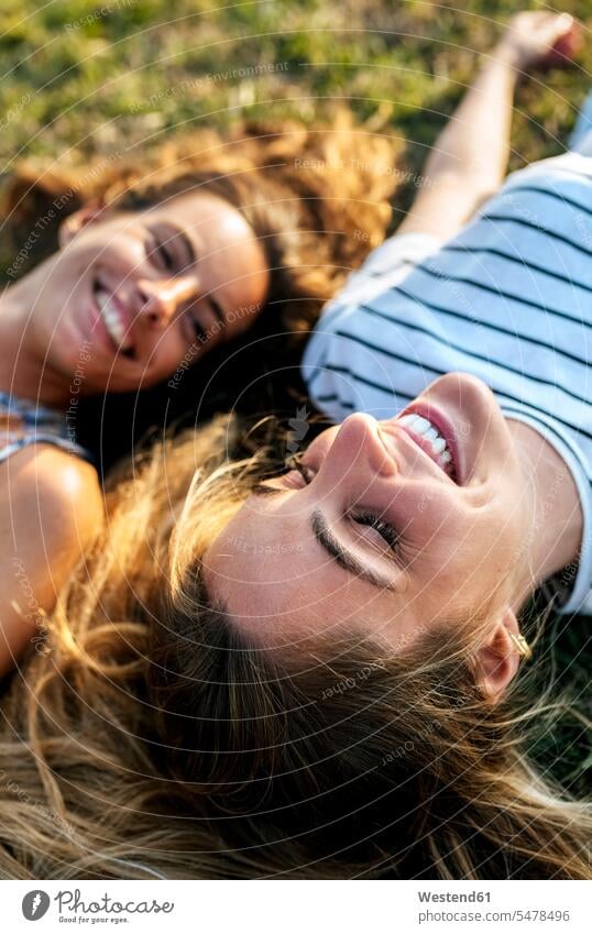 Lächelnde junge Frau entspannt sich mit Schwester auf dem Feld Farbaufnahme Farbe Farbfoto Farbphoto Außenaufnahme außen draußen im Freien Spanien lächeln Tag