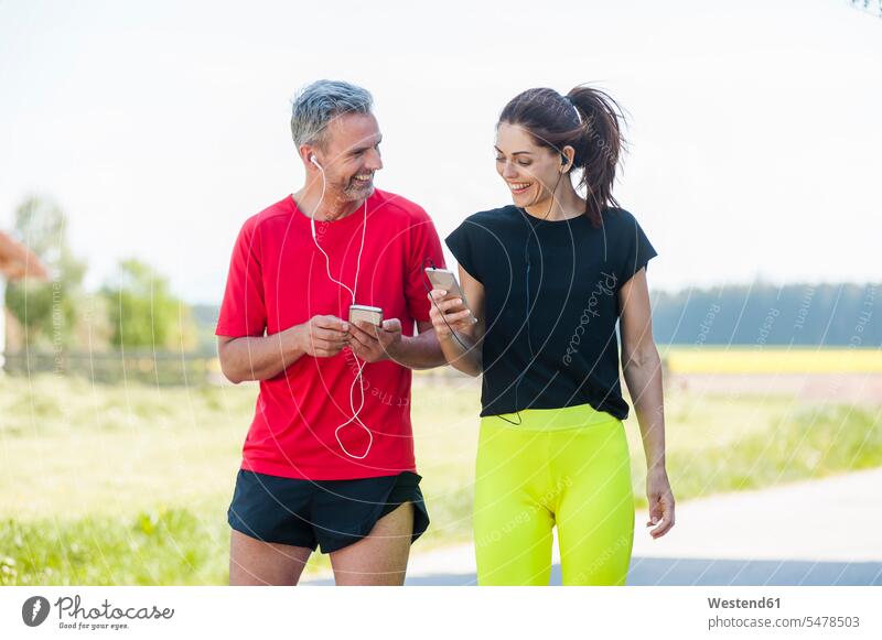 Paar benutzt Smartphones während des Trainings telefonieren anrufen Anruf telephonieren Pärchen Paare Partnerschaft Jogger Sportler iPhone Musik hören lächeln